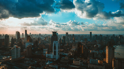 Obraz premium Aerial view of modern city skyline at sunset with dramatic clouds and river