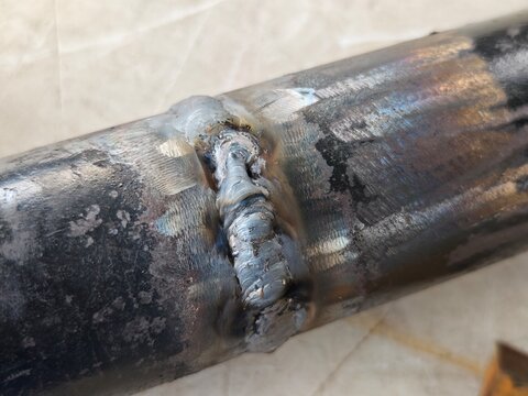 Close-up of pipe cover pass weld with visible welding defect on butt joint. Industrial metal fabrication inspection concept showing poor weld quality and repair requirement.