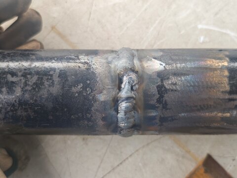 Close-up of pipe cover pass weld with visible welding defect on butt joint. Industrial metal fabrication inspection concept showing poor weld quality and repair requirement.