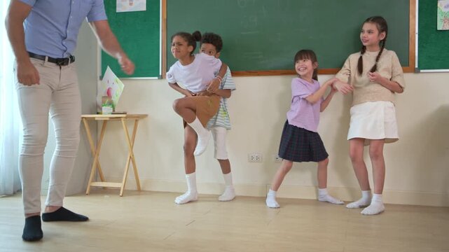 Diverse group of school children enjoying dance activity with teacher in an international classroom, encouraging active learning and teamwork