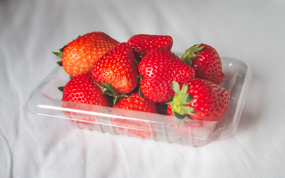 Strawberries in plastic box on white background. Healthy food.