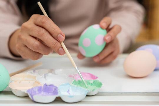 close up hand painting and decorating colorful egg at home on easter day