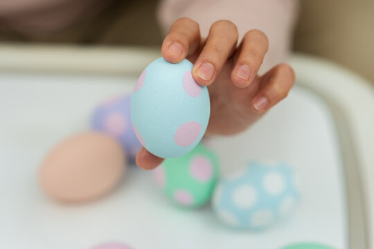 close up hand holding colorful egg while celebrating on easter day on table at home