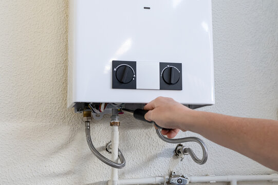 Professional technician using a screwdriver to perform maintenance and repair on a gas water heater, ensuring proper functioning and reliable hot water supply for residential or commercial heating