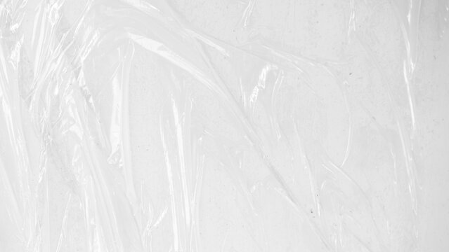 plastic transparent cellophane bag on white background. The texture looks blank and shiny. The plastic surface is wrinkly and tattered making abstract pattern