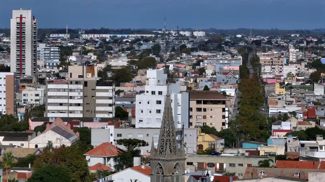 Telephoto aerial over Rio Grande rooftops with ornate gothic church spire in foreground and residential cityscape stretching to the horizon