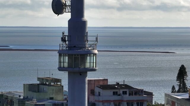 Telephoto close-up of communications tower with observation deck and antennas against wide lagoon backdrop in Rio Grande