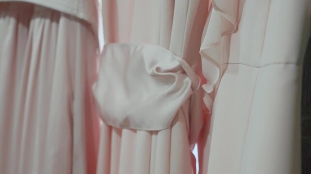 A detailed close-up shot of elegant blush pink bridesmaid dresses, focusing on a smooth satin sash tied at the waist, showcasing soft fabric textures and feminine wedding style.