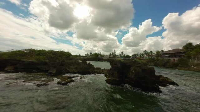 FPV drone shot flying around rocky headland with turquoise water in Boca de Yuma, Dominican Republic. aerial