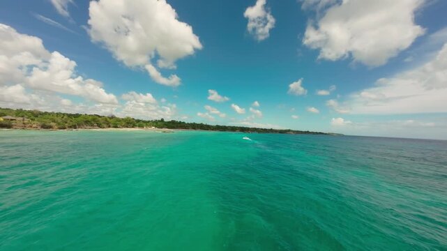 FPV drone flight over clear turquoise water along coast of Boca de Yuma, Dominican Republic. Aerial forward, copy space