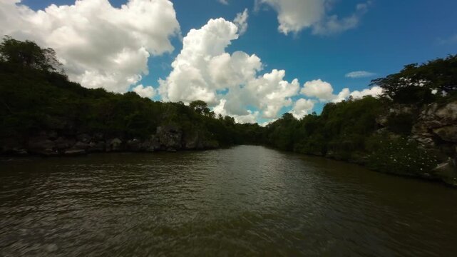 FPV drone flight up Yuma river, with lush green jungle on banks in Boca de Yuma, Dominican Republic. Aerial forward