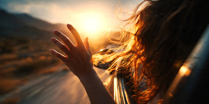 Close-up of a young woman&rsquo;s hand reaching out of a moving car window during a sunset road trip, wind flowing through her fingers, warm golden hour light, freedom and travel lifestyles.