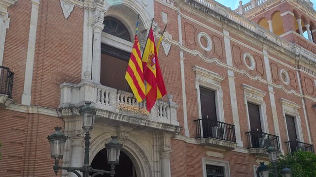 Vibrant yellow and red national banners flutter outside the historic brick and stone facade of the baroque episcopal residence in the heart of the old city