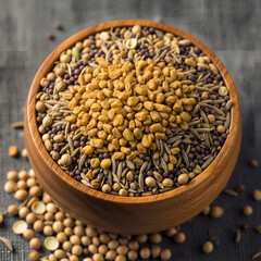 Fototapeta premium Close-up of a wooden bowl filled with a variety of dried seeds, including fenugreek, mustard, and cumin, ready for culinary use.