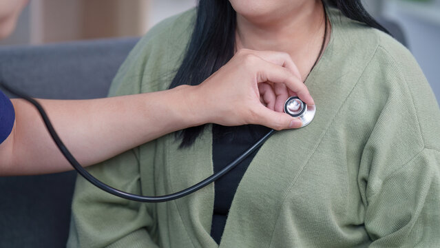 Asian healthcare professional using stethoscope on woman patient