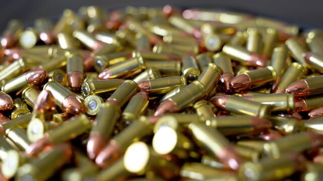 Pile of 9mm bullets rotating in circular formation. Close up of ammunition cartridges spinning with metallic shine