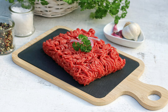 Frisches rohes Rinderhackfleisch auf Schieferplatte mit Knoblauch, Pfeffer und Petersilie garniert.