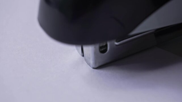 Close up of a stapler head fastening a textured blank white paper document