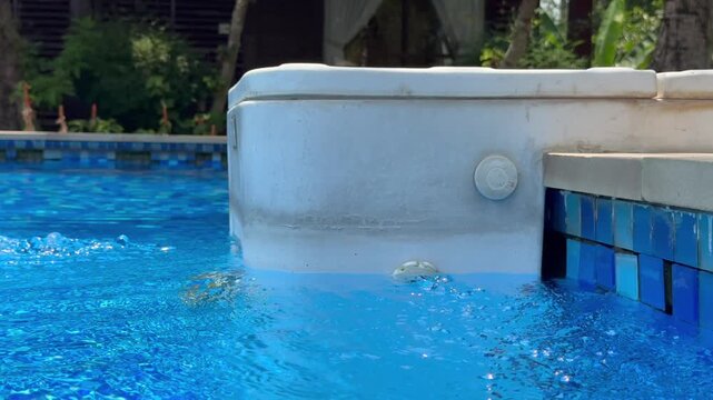 Close-up of a swimming pool filtration outlet with active water circulation and bubbles. Clean water flow from pool return jet demonstrating filtration system, maintenance process, water purification