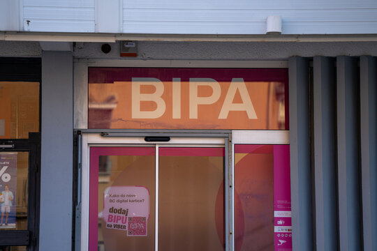 Exterior View of a BIPA Health and Beauty Store Entrance with Pink Branding and Signage in a European City Daytime