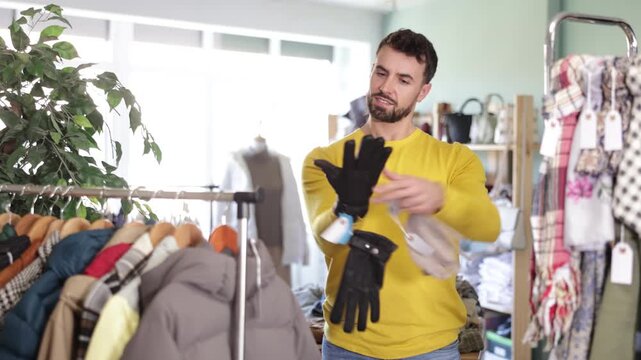 Customer inspect at products in store and pick out clothes. Man choose and try on gloves. Style and fashion type look, modern trends.