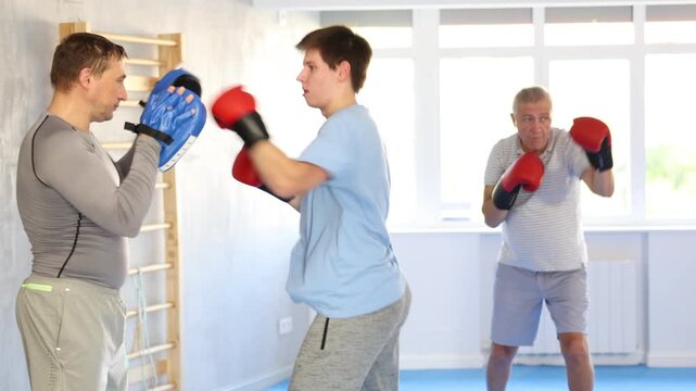 Young man and adult man training boxing punches in studio 