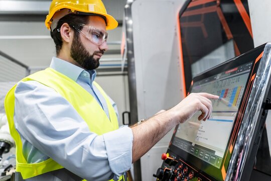 Young engineer wearing reflective clothing using touch screen machine