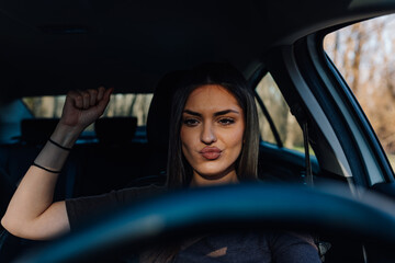 Naklejka premium Young woman driving car making a fist