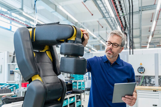 Engineer with tablet inspecting industrial robot in modern factory