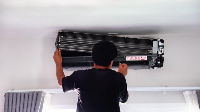 Professional technician disassembling and carefully reassembling a wall-mounted air conditioner blower fan during a deep cleaning and maintenance service.