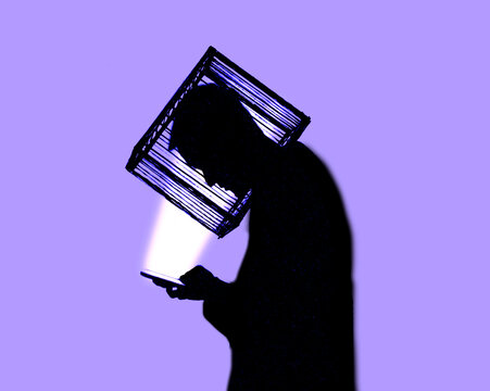 Silhouette of person with head in cage looking at smartphone
