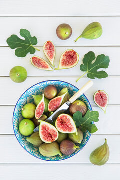 Top view of fresh healthy figs in a bowl on a white wooden table