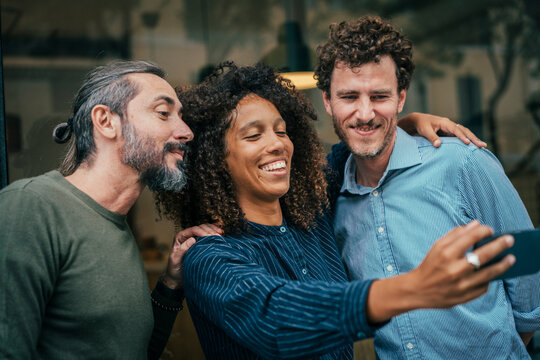 Business professionals holding smartphone and taking selfie at street