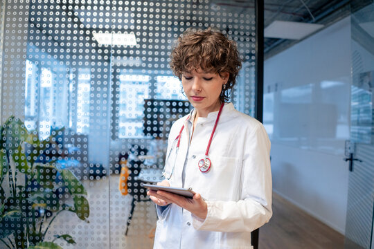 Young doctor using tablet PC in front of spotted glass at office