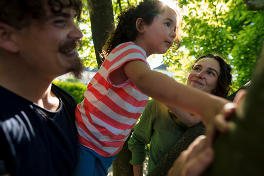 Parents spending leisure time with daughter on tree at park