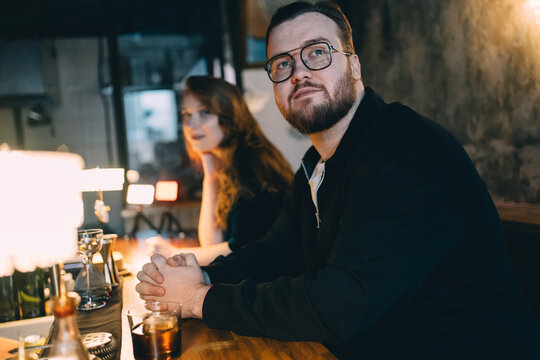 Man and woman waiting for a cocktail at a bar counter