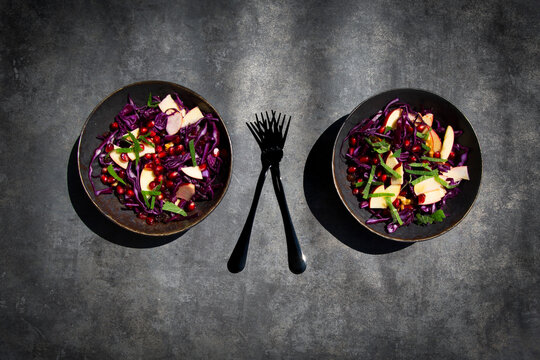 Red cabbage salad with apple and pomegranate on concrete