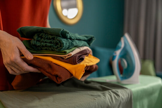 Hand holding folded clothing for ironing at home