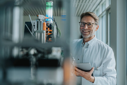 Scientist in laboratory monitoring sorting machine with tablet