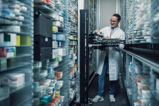 Pharmacist operating an order picking machine in a pharmacy
