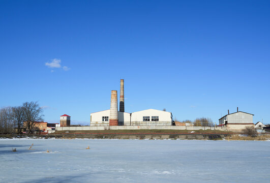 Old factory by frozen lake in Bucha Ukraine under blue sky