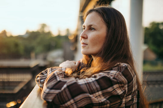Woman waitingaiting thoughtfully at the railway station during sunset