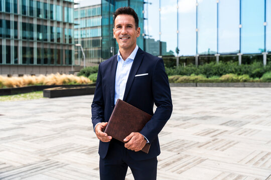 Smiling corporate manager holding folder in financial district