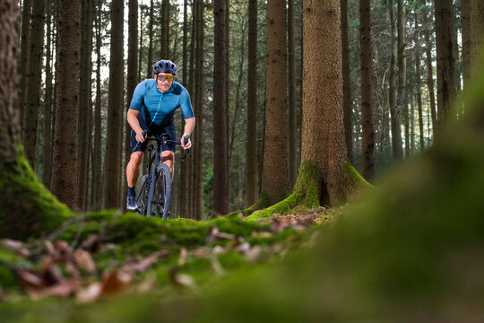 Cyclist riding gravel bike on a forest trail in Germany
