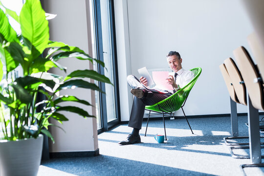 Smiling manager reading document and holding tablet in office