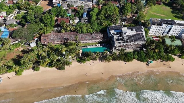 Drone shot of coastal hotels and buildings situated along the beach shoreline. Mirissa, Sri Lanka