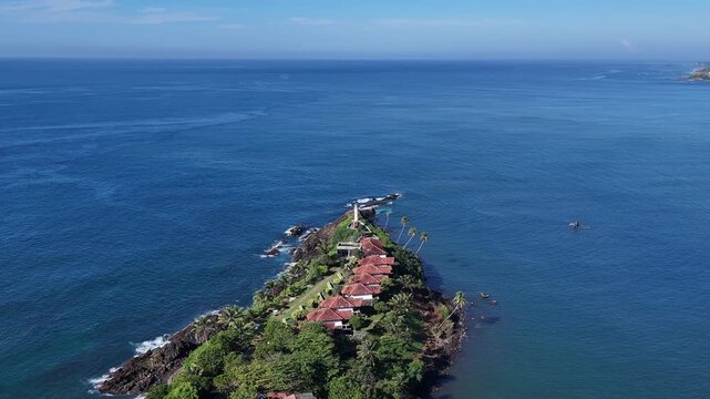 Aerial panorama of a headland jutting into the sea with architecture and a lighthouse. Mirissa, Sri Lanka