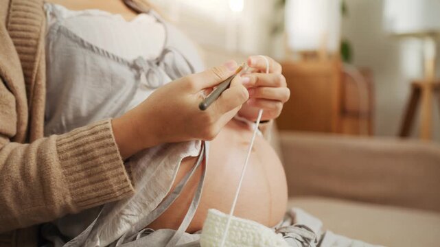 Close-up of a pregnant woman knitting baby booties for mindfulness and stress relief at home.