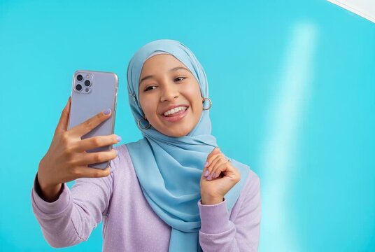 Happy Young Muslim Woman in Hijab Recording Video on Smartphone