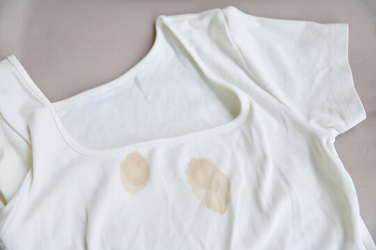 Close up of yellow food or coffee stains on a white t-shirt, dirty clothes concept